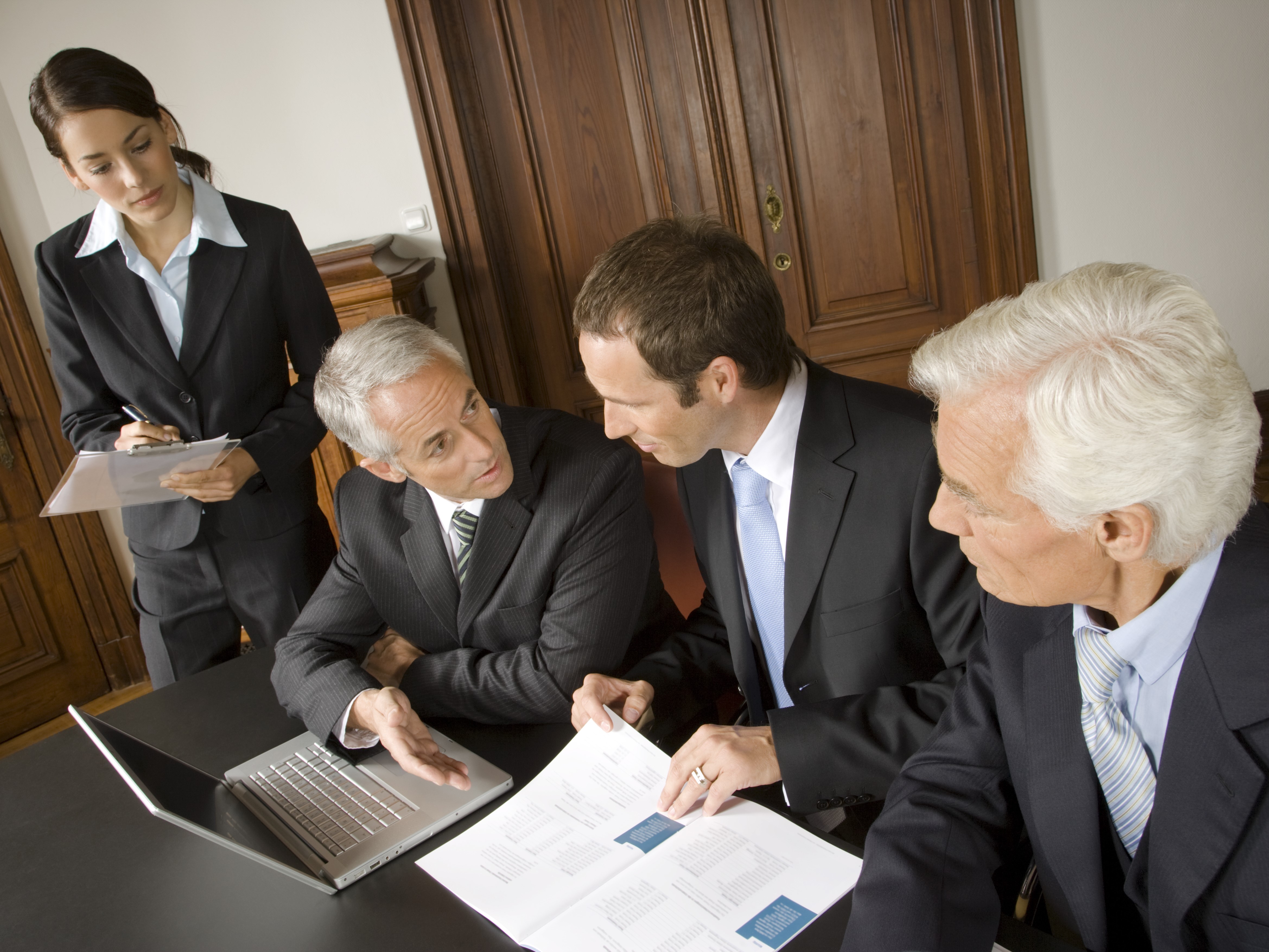 Un groupe de quatre personnes ressemblées autour d'un bureau avec des documents et un ordinateur portable.