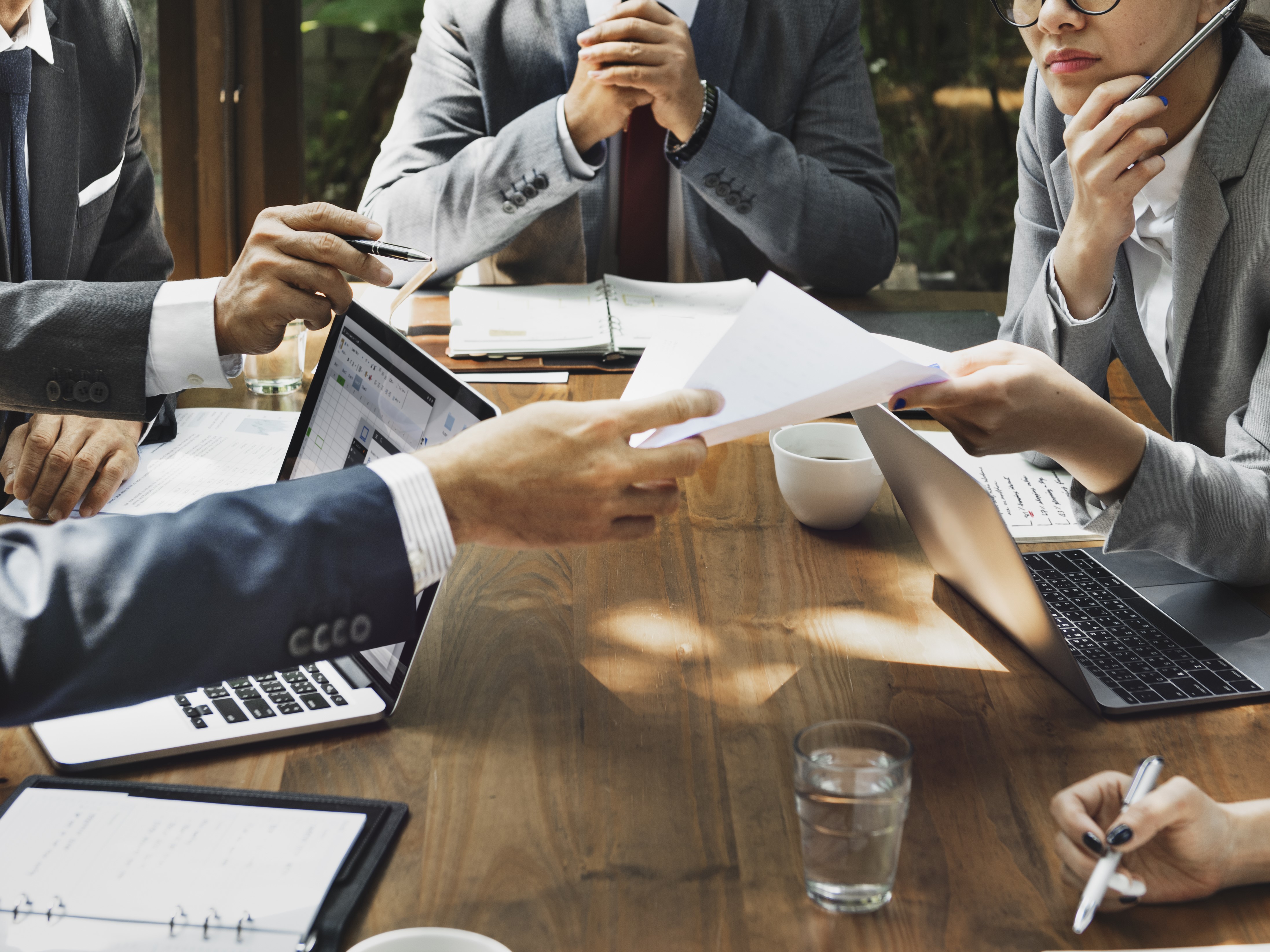 3 personnes à une table avec un ordinateur portable et des documents.