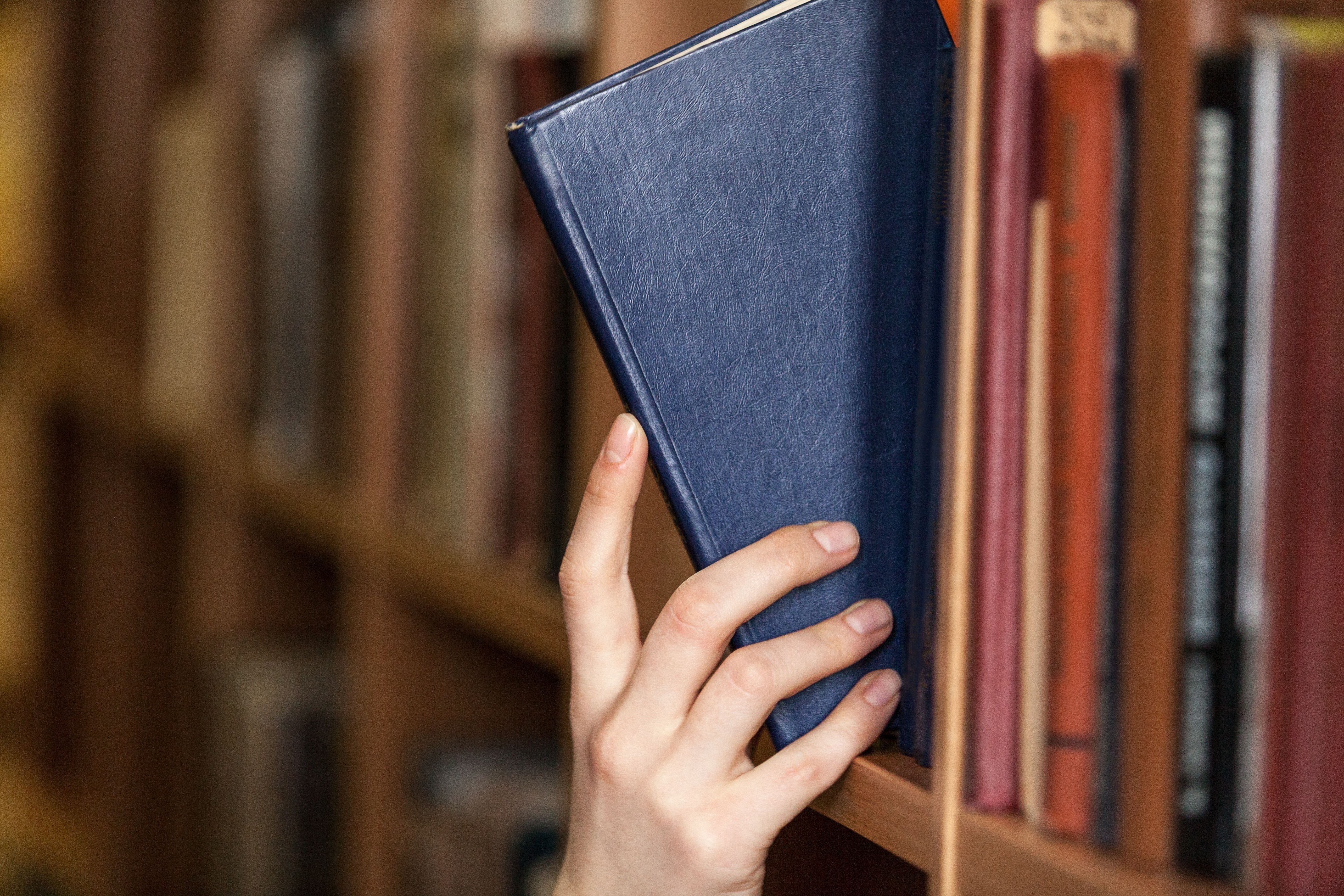 Person pulling out a book from a library