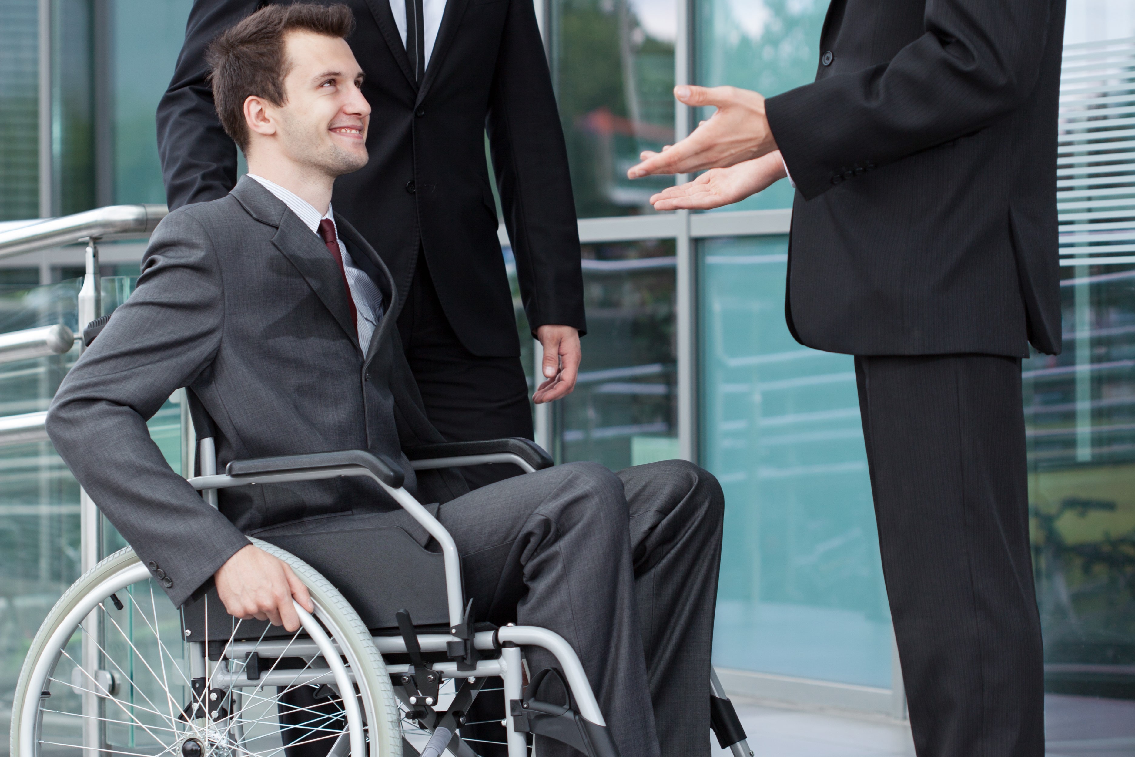 A person in a weelchair talking to two other persons