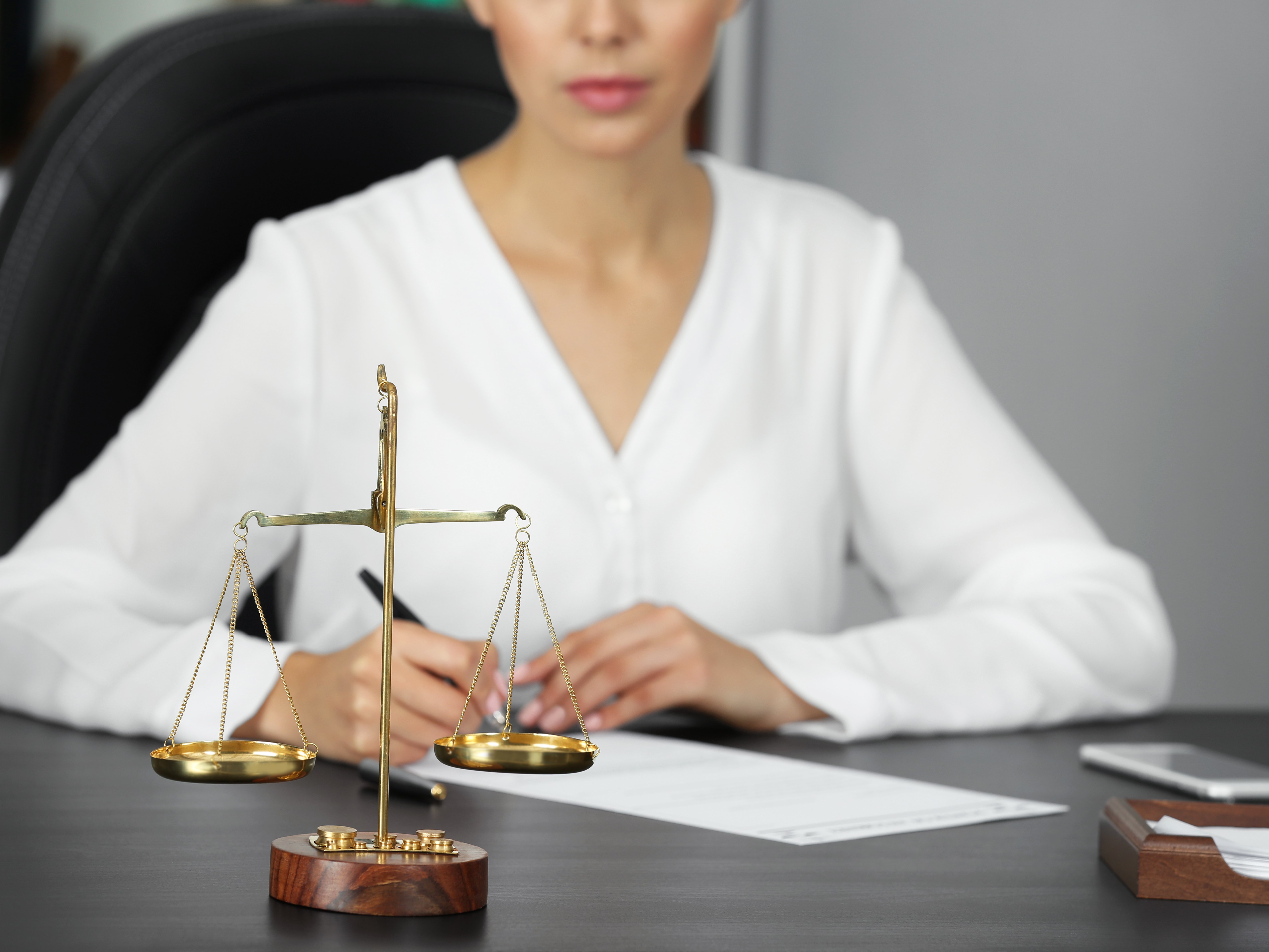 Femme avec une chemise blanche à une table avec une balance.