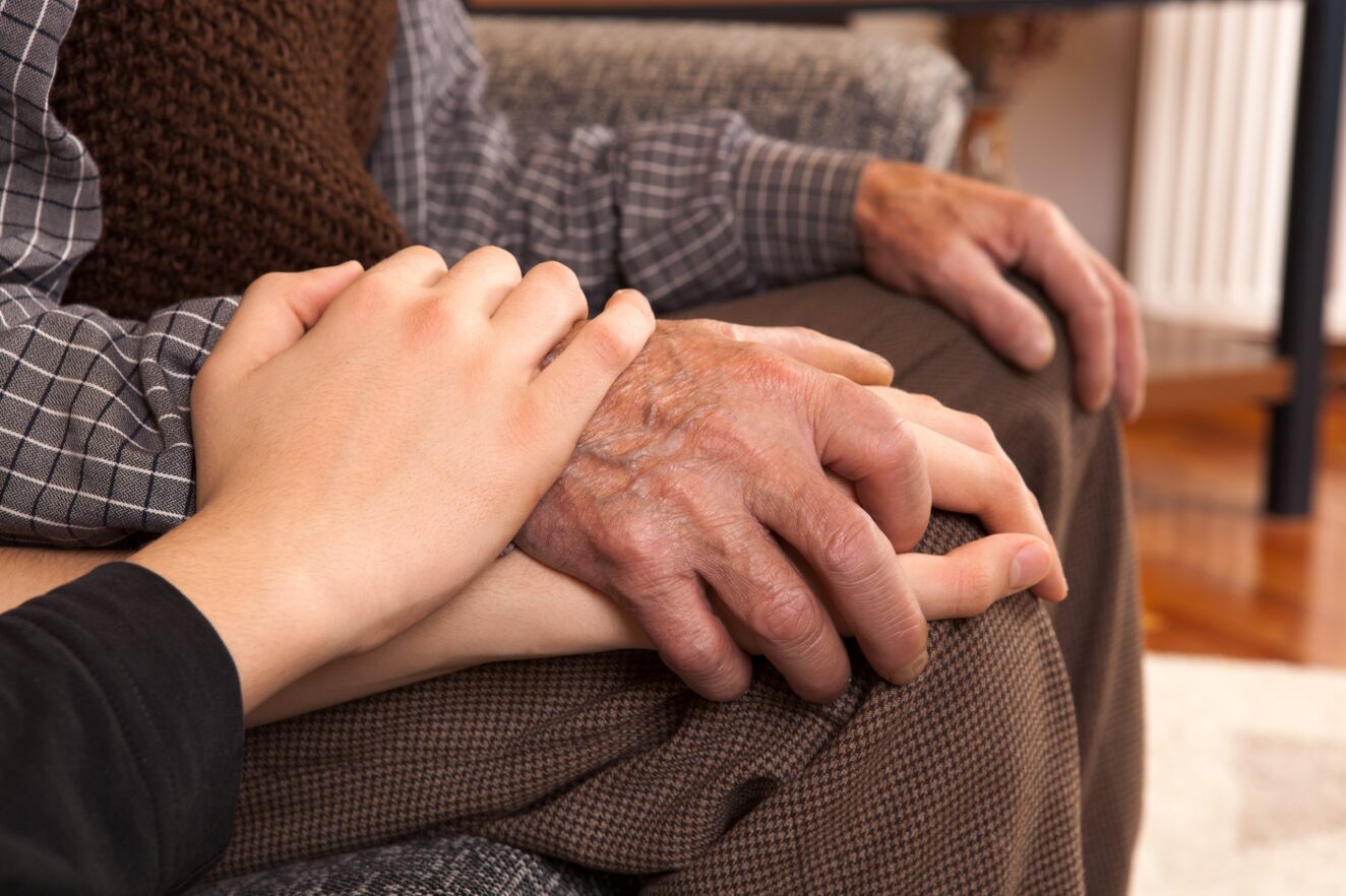 A person holding the hand of an older person